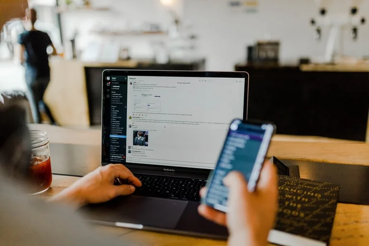 KPIs en marketing: persona con un portatil y un celular revisando un sitio web.