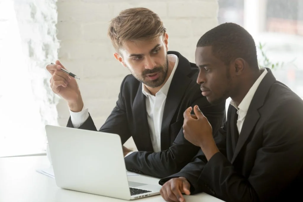 Brokers trading: Dos ejecutivos conversando frente a un computador